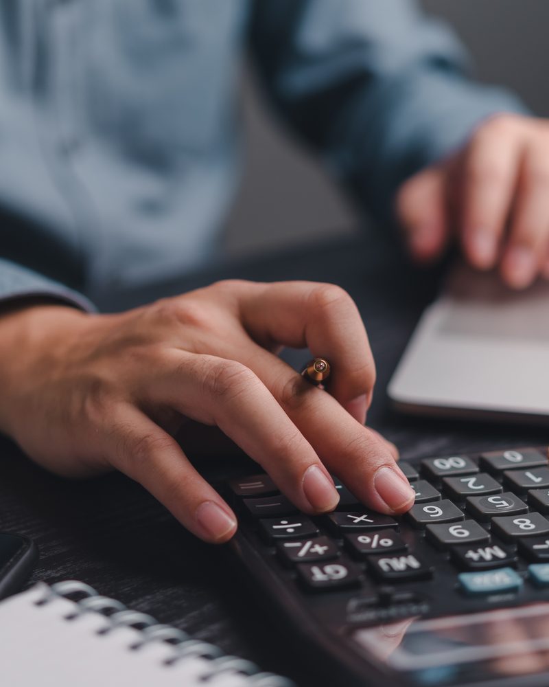 Hands working on a laptop and calculator